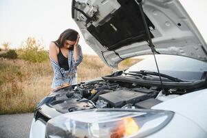 schön sexy Frau in der Nähe von ein gebrochen Wagen. verwirrt Frau tut nicht kennt Was zu tun foto