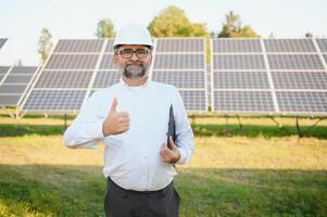 Solar- Leistung Pflanze. Mann Stehen in der Nähe von Solar- Tafeln. verlängerbar Energie foto