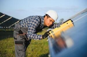 ein indisch männlich Arbeiter ist Arbeiten auf Installation Solar- Paneele im ein Feld foto