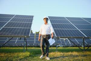 ein indisch männlich Ingenieur Arbeiten auf ein Feld von Solar- Tafeln. das Konzept von verlängerbar Energie foto