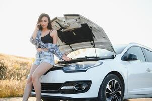 Frauen reden auf das Telefon Über Problem mit ihr Auto sie kippen. jung sexy Mädchen berät auf das Telefon während Auto Reparatur foto