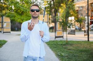 jung blind Mann mit Telefon und Senden Stimme Botschaft foto