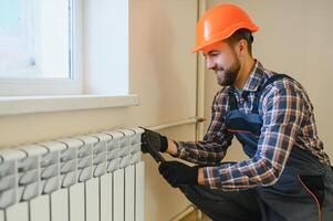 jung Mann Klempner Überprüfung Kühler während Installation Heizung System im Wohnung foto