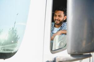 jung indisch LKW Treiber Sitzung hinter Lenkung Rad im ein Kabine foto