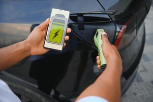 Mann Einstecken im elektrisch Auto draußen Büro im Auto Park Laden foto