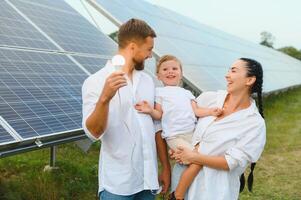 das Konzept von verlängerbar Energie. jung glücklich Familie in der Nähe von Solar- Paneele foto