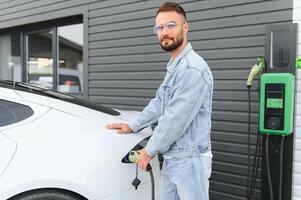 stilvoll Mann Einsätze Stecker in das elektrisch Auto Laden Steckdose foto