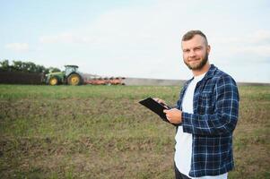 Einrahmer Kontrollen das Arbeit im das Feld Über es ist Tablette. Traktor im das Hintergrund foto