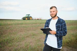 Einrahmer Kontrollen das Arbeit im das Feld Über es ist Tablette. Traktor im das Hintergrund foto