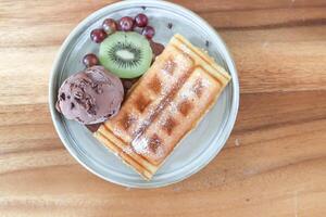 Waffel mit Eis Sahne und Obst oder Schokolade Eis Sahne mit Waffel, Traube und Kiwi Obst foto