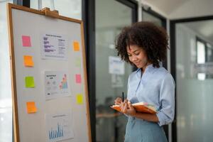 Geschäft Frau planen zu nehmen Anmerkungen, Arbeiten aus ein Strategie, Geschäft Projekt Planung foto