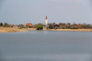 See mit ein Dorf und Kirche Turm foto