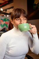 Porträt von ein Frau mit ein Tasse von Kaffee im ein Cafe foto