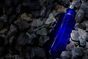 Parfüm dunkel Blau transparent Flasche im Kies oder Koralle Hintergrund foto