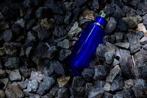 Parfüm dunkel Blau transparent Flasche im Kies oder Koralle Hintergrund foto