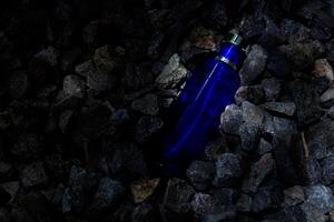 Parfüm dunkel Blau transparent Flasche im Kies oder Koralle Hintergrund foto