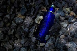 Parfüm dunkel Blau transparent Flasche im Kies oder Koralle Hintergrund foto