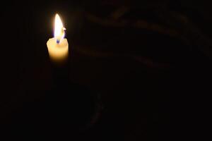 Single Kerze mit Flamme im das dunkel Ort, isoliert schwarz Hintergrund foto