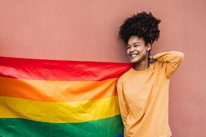 glücklich afrikanisch Fröhlich Frau feiern Stolz halten Regenbogen Flagge draussen - - lgbt Konzept foto