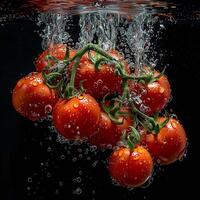 Tomaten fallen im Wasser mit Spritzen auf schwarz Hintergrund. foto