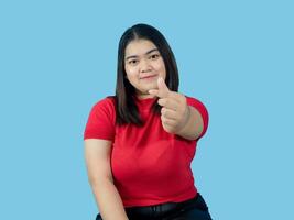 Porträt Mädchen jung Frau asiatisch mollig Fett süß schön ziemlich einer Person tragen ein rot Hemd ist Sitzung lächelnd genießen glücklich suchen Beeindruckend zu Copyspace imaginär auf das Blau Hintergrund foto