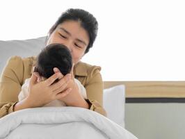 Mutter halten Kopf von ihr Neugeborene Baby Mädchen oder Junge im Hände. liebend Mama Sitzung im Weiß Bett und halten Säugling Kind. foto