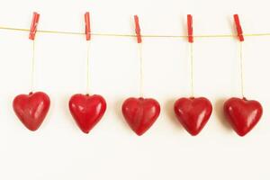 fünf rot Herzen hängen von ein Linie mit Heringe. Weiß Hintergrund foto