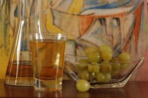 ein Glas von Apfel Saft und ein Schüssel mit Trauben foto
