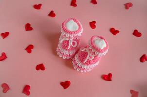 gestrickt Rosa Booties Baby Socken auf Rosa Hintergrund mit Herzen foto