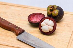 Königin von Frucht. Mangostanfrüchte und Messer auf das hölzern Platte. foto