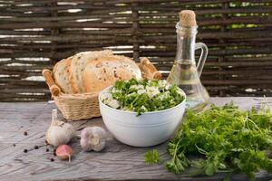 Salat mit Tofu und Petersilie. ein Schüssel von Salat auf das Hintergrund von ein Flasche von Butter und Stücke von Brot. Knoblauch und Pfefferkörner nahe. foto