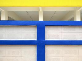 Hintergrund abstrakt Blau und Gelb Linie Muster von Beton Block Mauer im Vorderseite von Weiß Gebäude foto