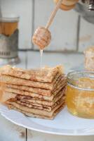 ein Mann gießt Honig auf Pfannkuchen und Getränke Tee von ein Samowar, Russisch Tradition von feiern maslenitsa foto