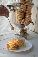 Russisch Pfannkuchen mit Honig und ein Tasse von Tee von ein Jahrgang Samowar maslenitsa Festival Konzept foto