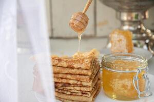 Russisch Pfannkuchen mit Honig und ein Tasse von Tee von ein Jahrgang Samowar maslenitsa Festival Konzept foto