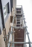 Konstruktion von Stahl Gerüst in der Nähe von Gebäude zum Renovierung Arbeit, vertikal Gerüst Formen verschiedene Gitter, modern foto
