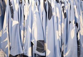 Blau und Weiß Sommer- Blusen auf ein Aufhänger im das speichern, hell Sommer- Kleider foto