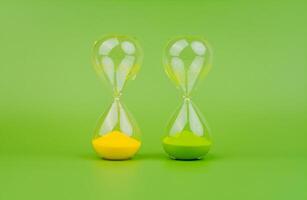 Grün und Gelb Sanduhr auf ein Licht Grün Hintergrund, Regeln von Zeit und Countdown Zeit Verfahren. foto