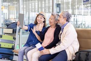 Gruppe von asiatisch Familie Tourist Passagiere mit Senior ist mit Handy, Mobiltelefon Telefon zu nehmen Selfie Foto beim Flughafen Terminal während Ferien Reise und lange Wochenende Urlaub Konzept