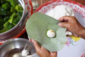 Hände halt Banane Blatt zu wickeln Teig Brötchen zum Kochen thailändisch traditionell Nachtisch. Konzept, thailändisch Lebensmittel. Wie zu kochen, Schritt von Kochen. thailändisch traditionell Lebensstil, bereiten Essen zum kulturell Feier. foto