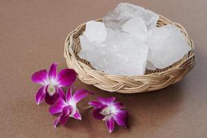 Kristallklare Alaunsteine oder Kaliumalaun auf Körbchen, verziert mit Blumen. nützlich für Schönheits- und Spa-Behandlungen. Verwenden Sie es, um Körpergeruch unter den Achseln als Deodorant zu behandeln und Wasser klar zu machen. foto