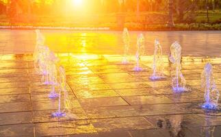 klein Brunnen auf das Bürgersteig, beleuchtet durch Sonnenlicht beim Sonnenuntergang oder Sonnenaufgang beim Sommer. foto