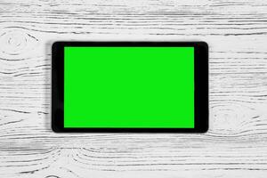 schwarz Tablette mit Grün Bildschirm auf ein hölzern Tabelle spotten hoch. Kopieren Raum Chroma Schlüssel Anzeige. foto