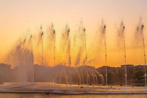 groß Brunnen auf das künstlich Teich, beleuchtet durch Sonnenlicht beim Sonnenuntergang im Taschkent Stadt Park beim Sommer. foto