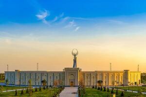 Usbekistan, Taschkent - - April 25, 2023 das Gebiet von das Park Neu Usbekistan mit Monument von Unabhängigkeit im das bilden von ein Stele mit ein Humo Vogel beim Dämmerung. foto