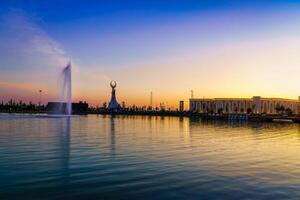 Usbekistan, Taschkent - - April 25, 2023 das Gebiet von das Park Neu Usbekistan mit Monument von Unabhängigkeit im das bilden von ein Stele mit ein Humo Vogel, Teich und Brunnen beim Dämmerung. foto