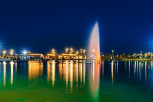 verschwommen Brunnen Wasser fließt im ein künstlich See im ein Nacht Park mit Laternen und Dekorationen. foto