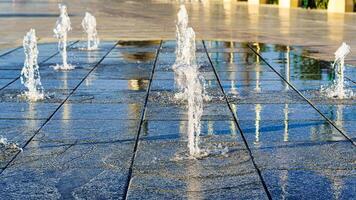 Streams von planschen klein Brunnen auf nass Pflasterung Platten, beleuchtet durch das Sonne im ein Sommer. foto