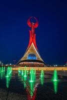 Usbekistan, Taschkent - - kann 5, 2023 beleuchtet Monument von Unabhängigkeit im das bilden von ein Stele mit ein Humo Vogel, Brunnen und winken Flaggen im das Neu Usbekistan Park beim nachts. foto