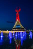 Usbekistan, Taschkent - - kann 5, 2023 beleuchtet Monument von Unabhängigkeit im das bilden von ein Stele mit ein Humo Vogel, Brunnen und winken Flaggen im das Neu Usbekistan Park beim nachts. foto